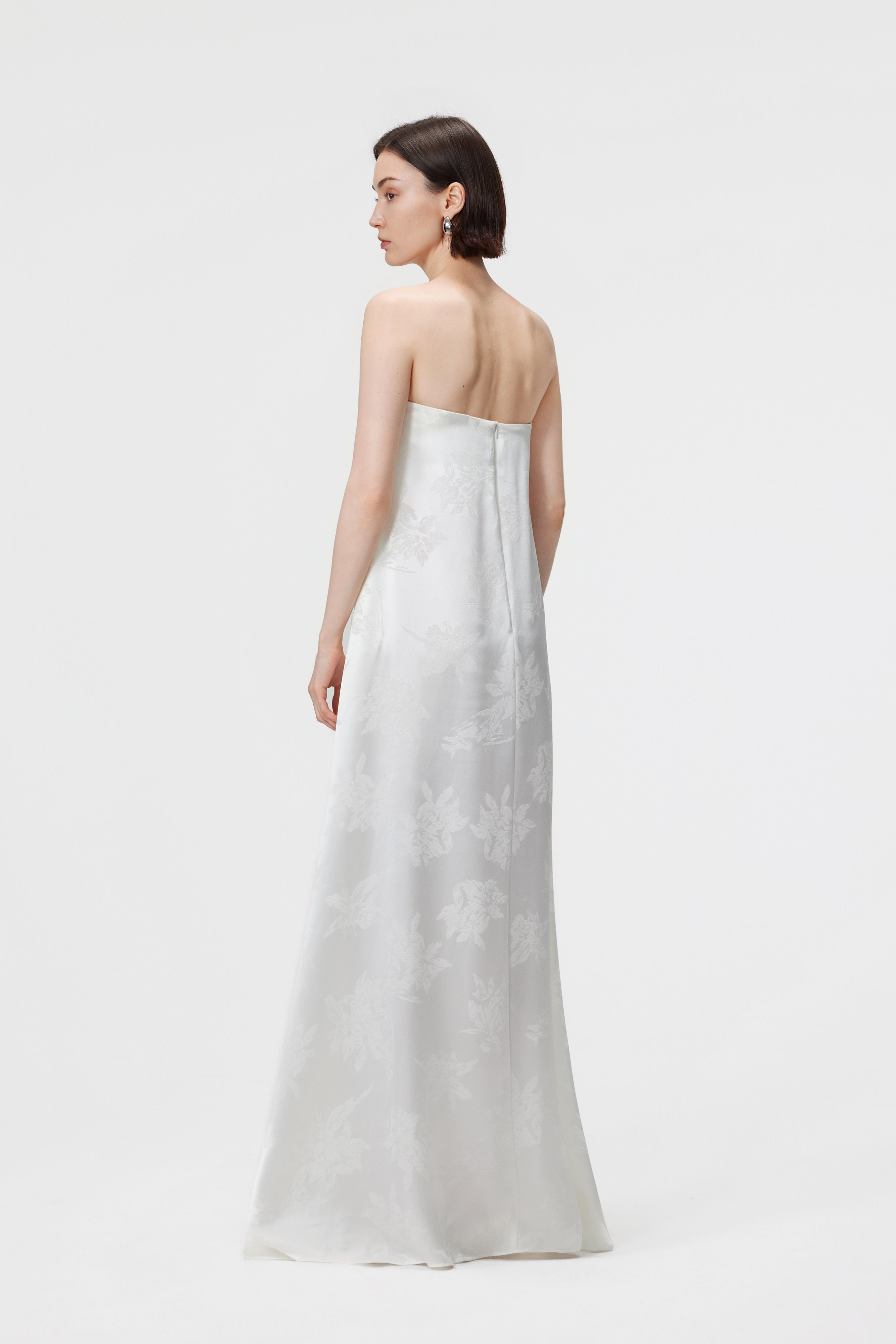 Back view of the Iris Jacquard Strapless Maxi Dress in White showing the elegant Bardot shoulder line and the invisible center-back zip closure for a seamless, minimalist finish.