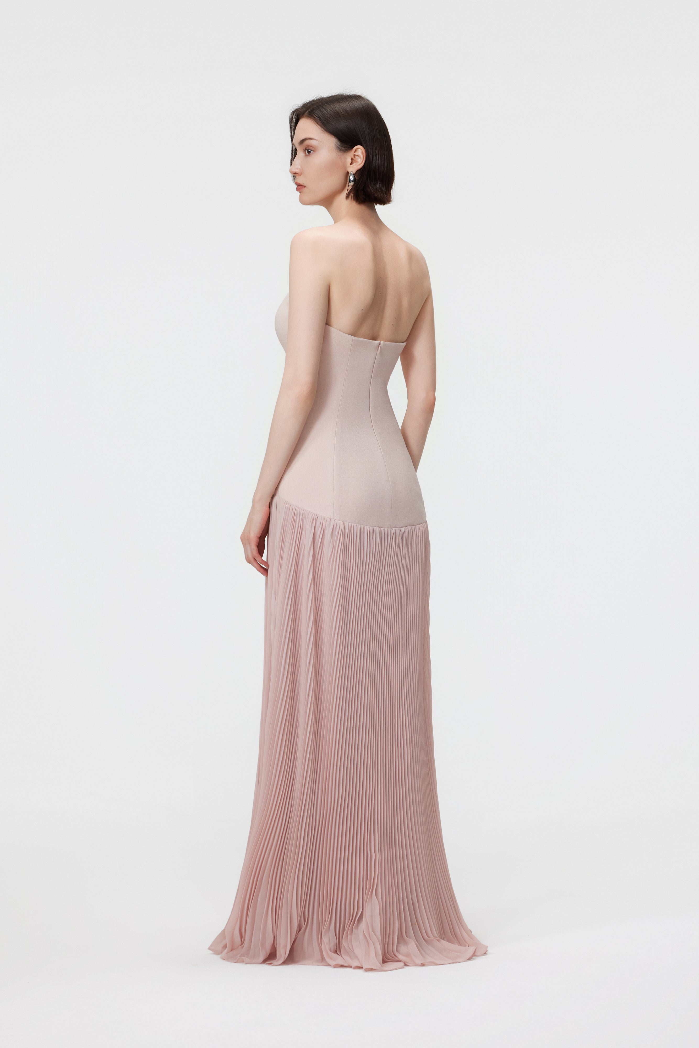 Back view of the Rosewater Luna gown, showcasing the clean lines of the bustier back and the fluid, floor-sweeping movement of the pleated skirt.