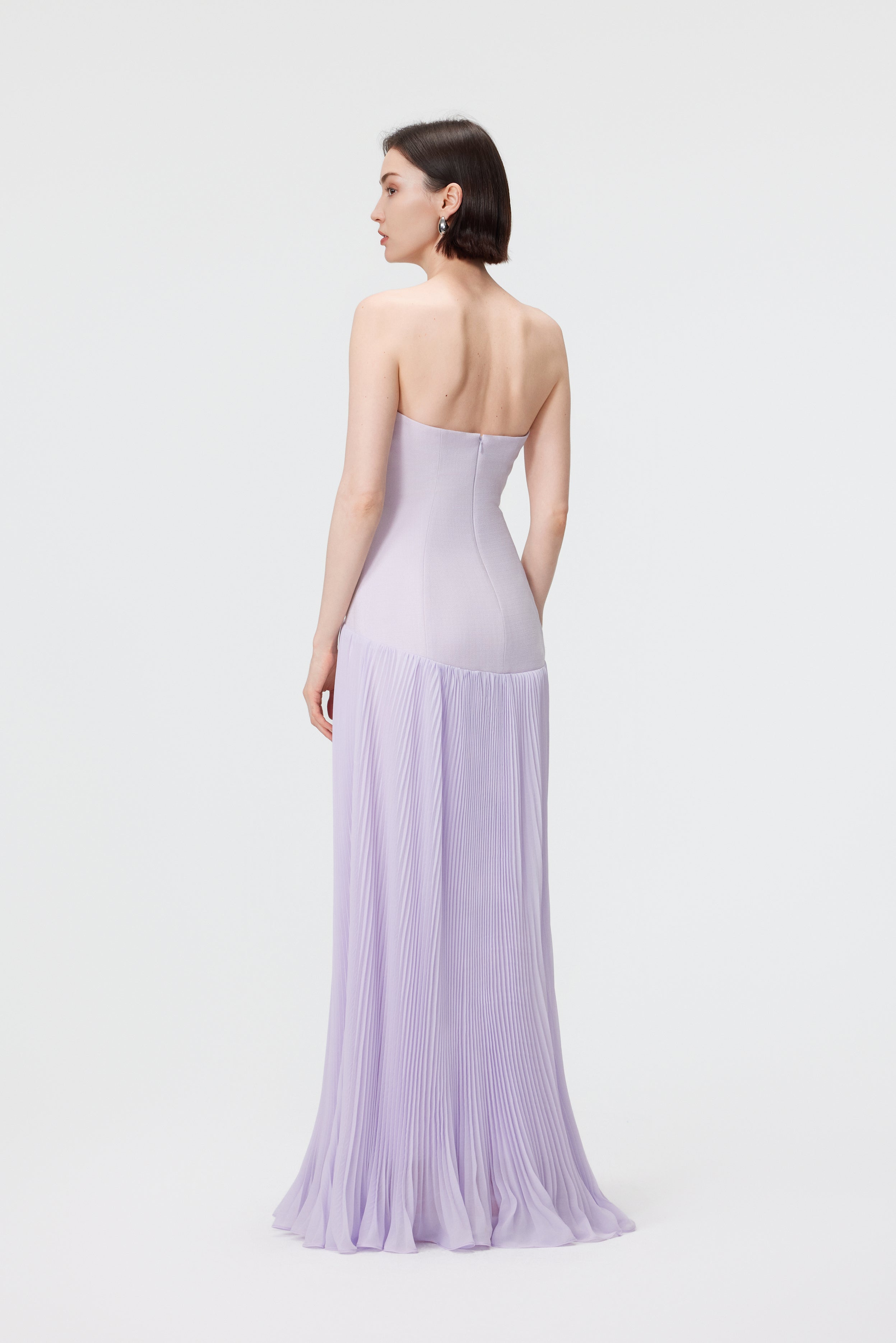 Back view of the Cloudy Lilac Luna gown, showcasing the precision-paneled back and the elegant, floor-sweeping drape of the pleated skirt.