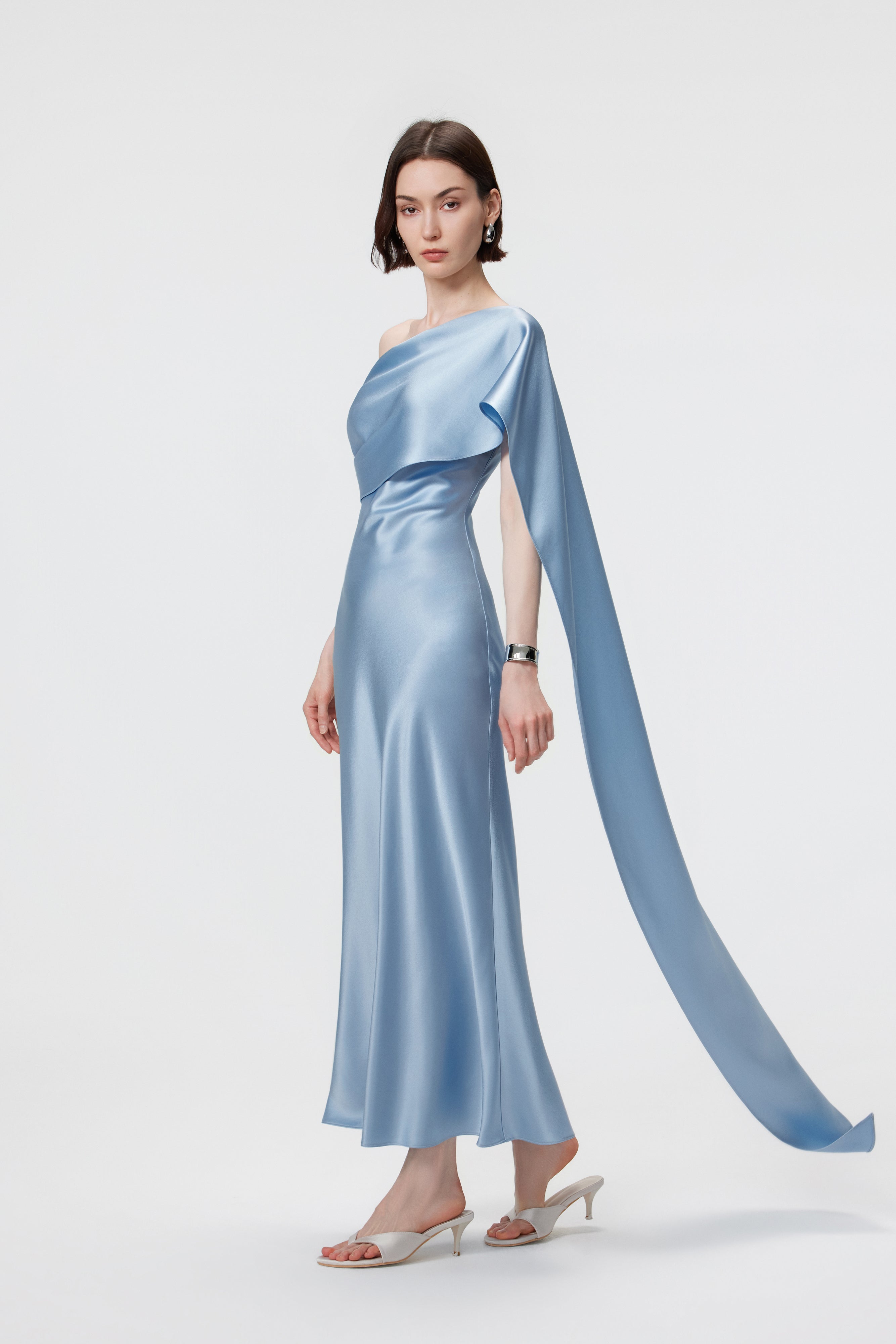 Side view of the Lyra dress in Glacial Mist; showcasing the seamless integration of the trailing scarf into the asymmetric shoulder drape.