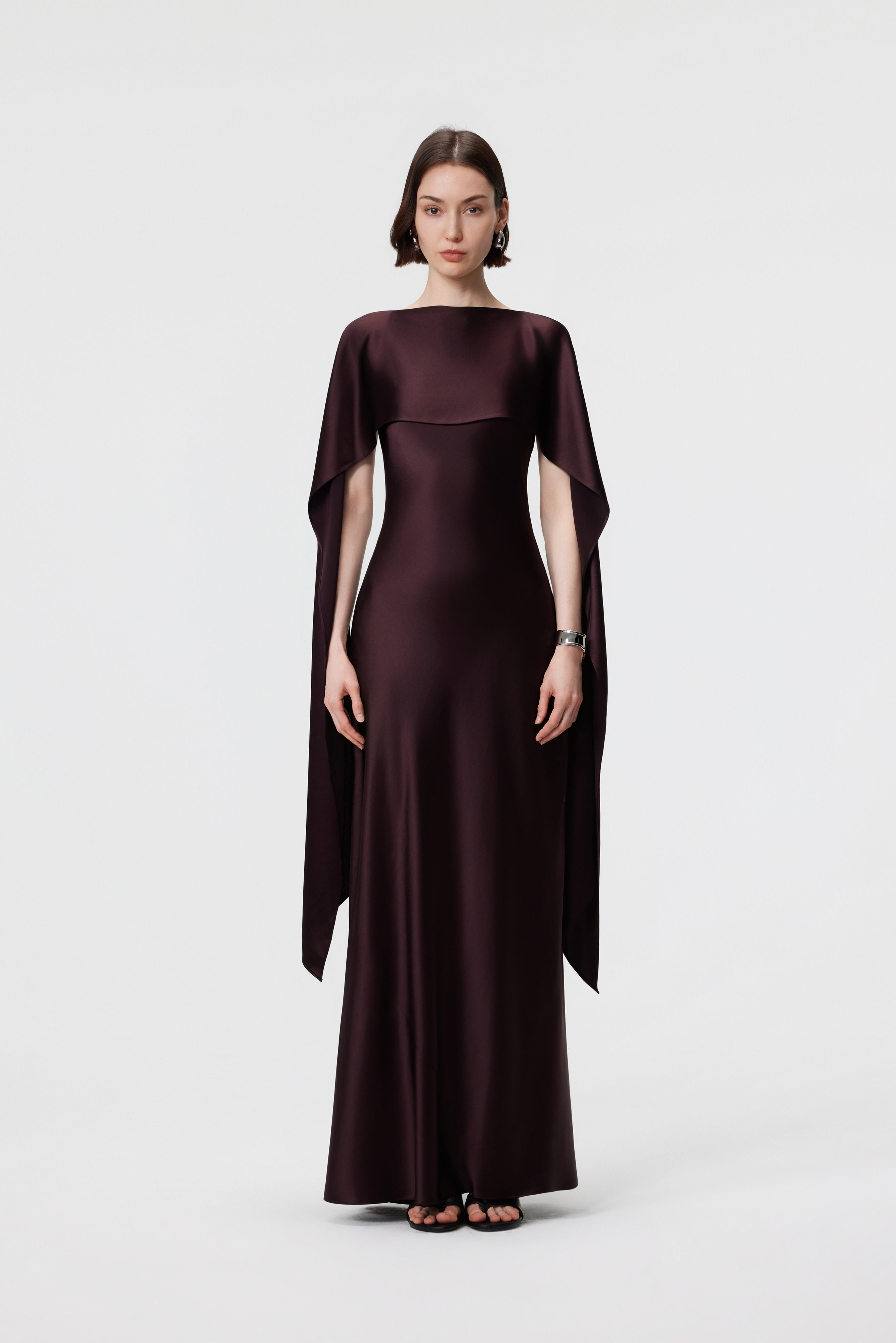 The AENSO Elara Gown in Espresso is styled as an architectural cape, a statuesque, high-coverage profile for formal evening receptions.
