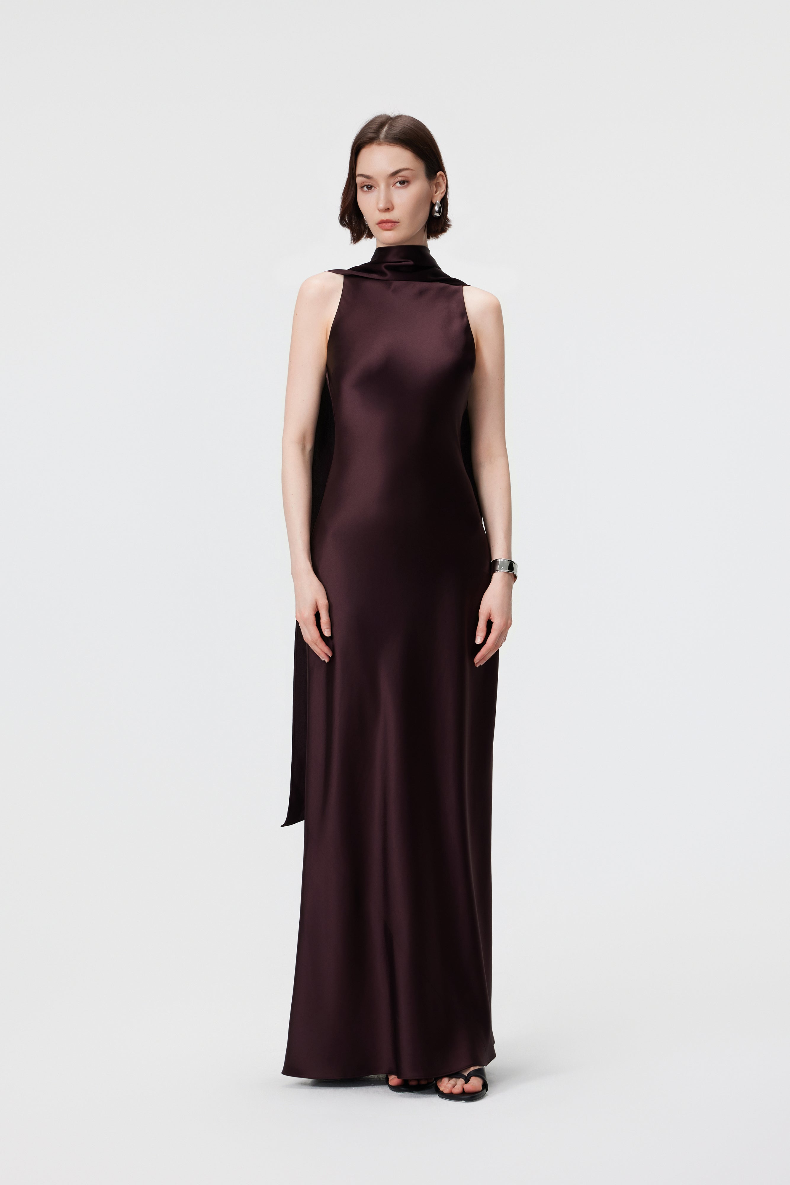 Front view of AENSO Elara Gown in Espresso, a luminous Naia™ Acetate satin dress featuring a sculptural high-neck and bias-cut silhouette.