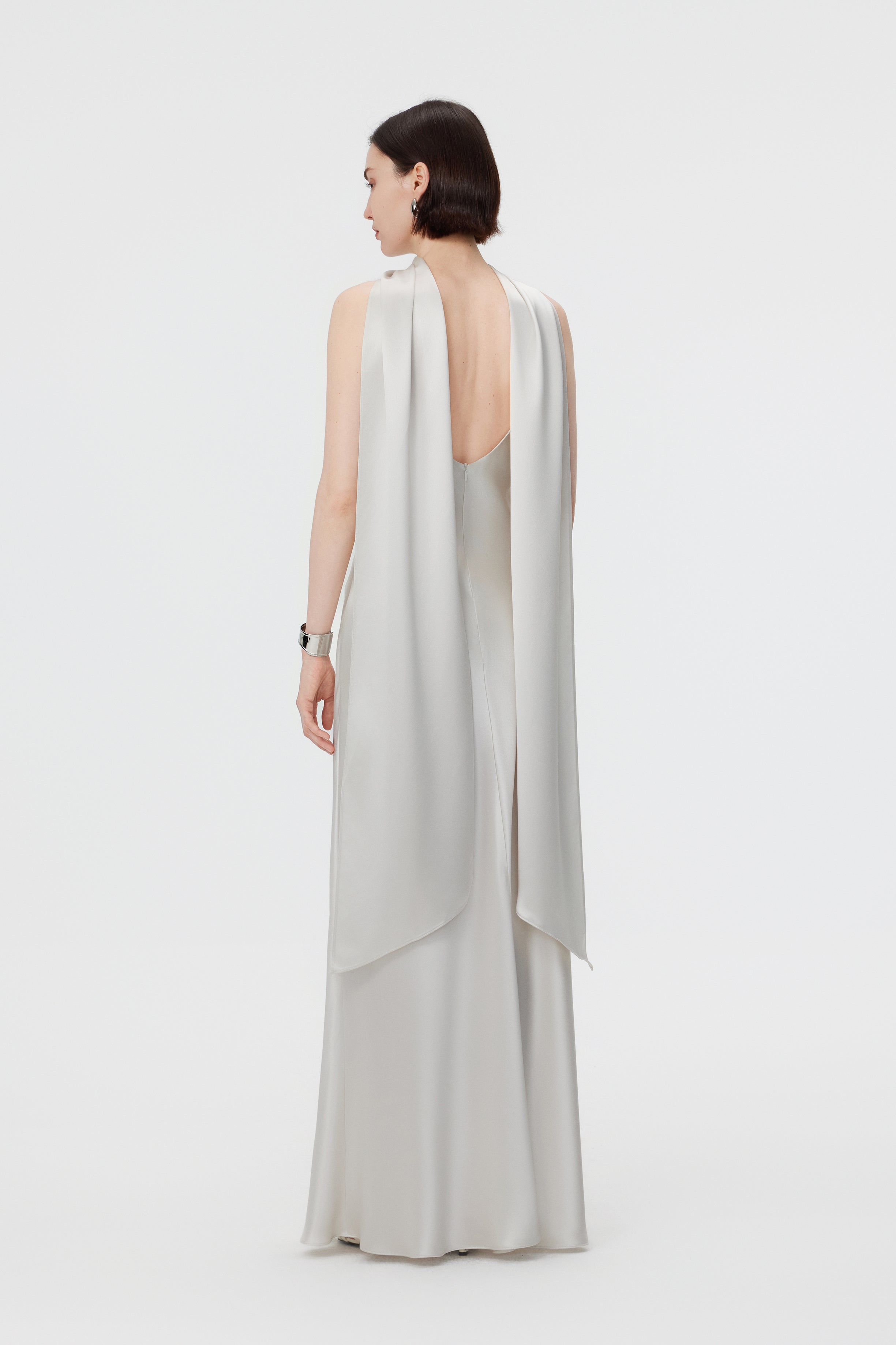 Back view of the AENSO Elara gown in Pearl; emphasizing the fluid, rhythmic trail of the high-luster Naia™ Acetate and the clean, minimal construction.