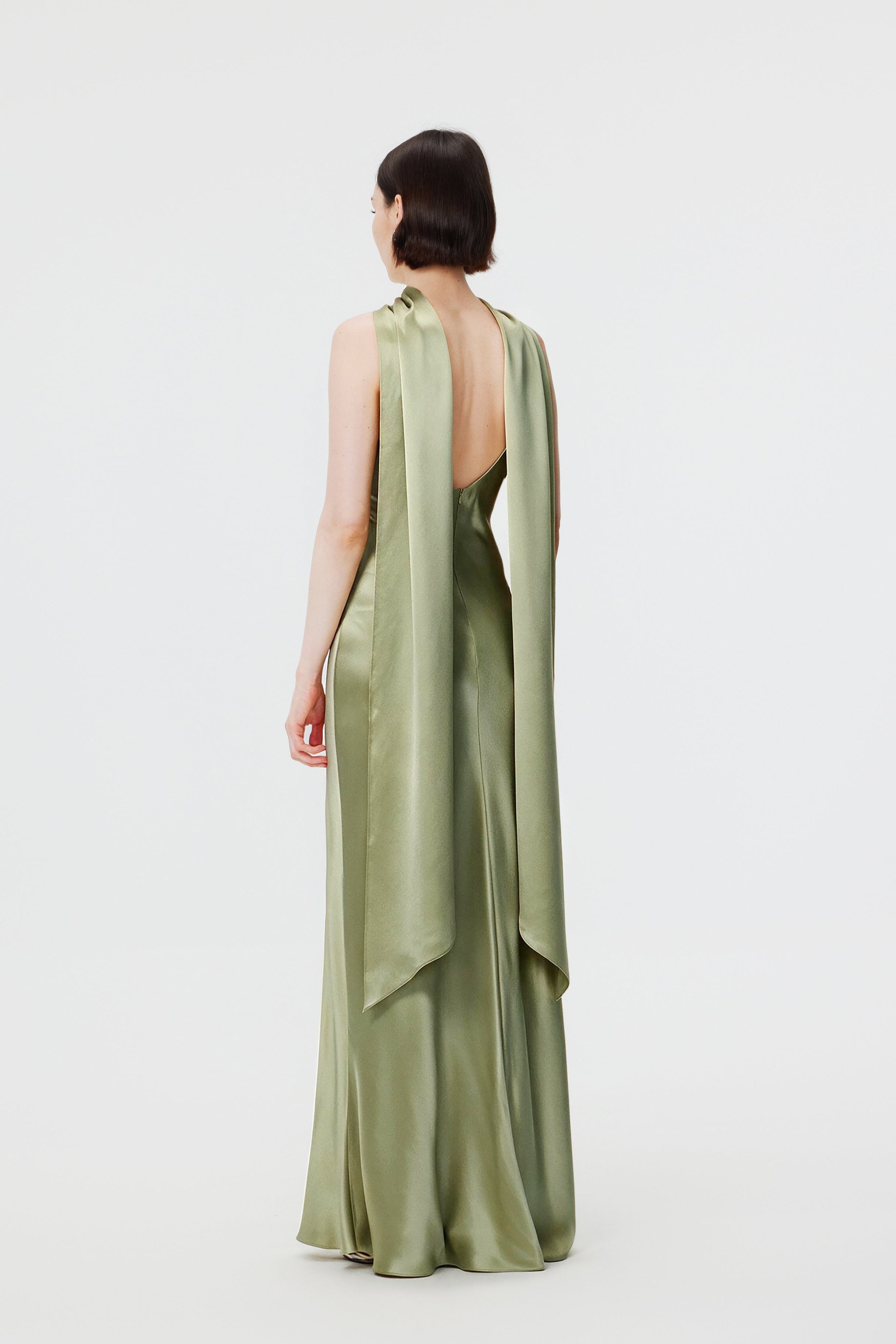 Back view of a floor-length Moss green satin evening gown showing the fluid drape and cape-like trail.