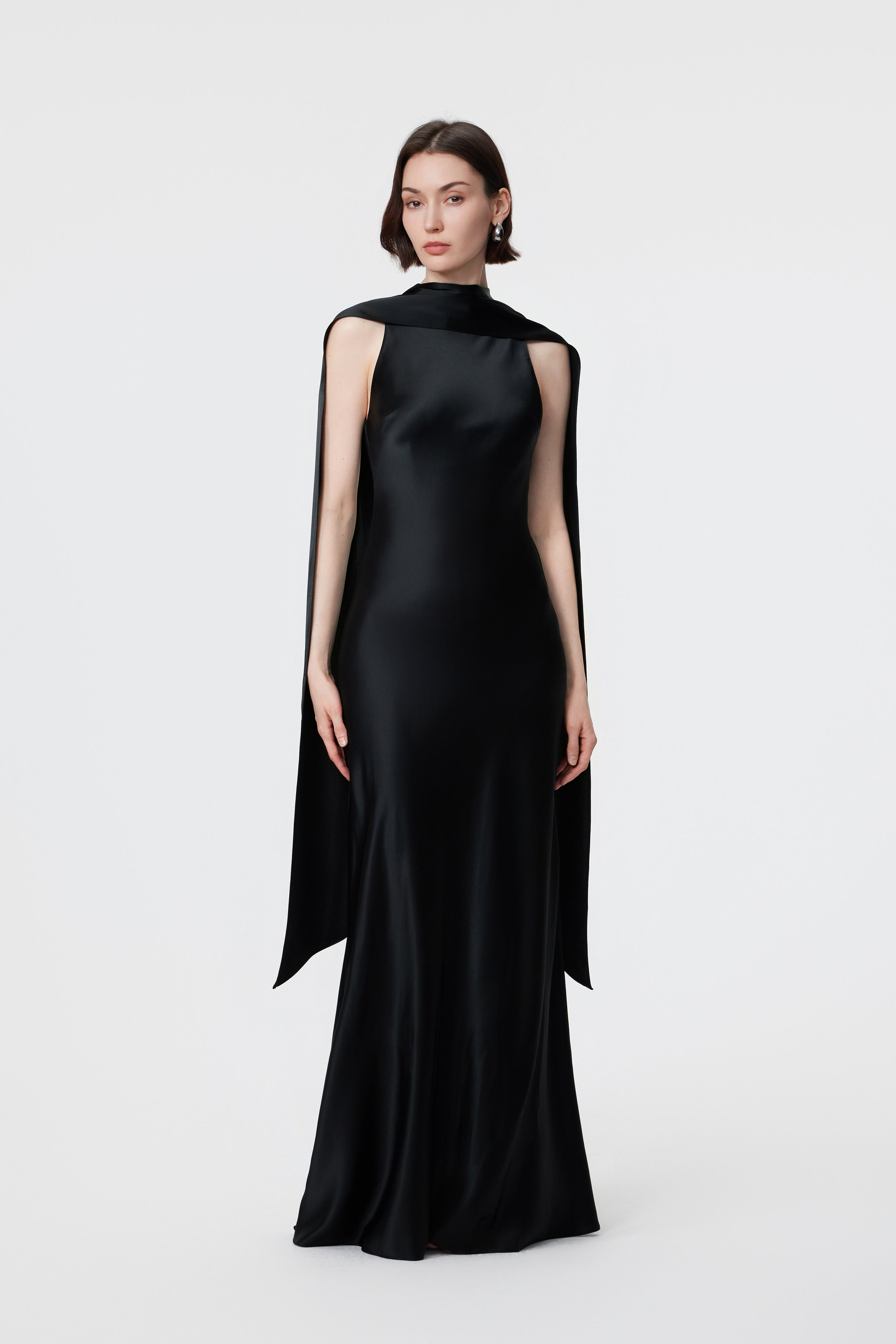 Static front view of the AENSO Elara gown in Black; a statuesque high-volume silhouette in lustrous Naia™ Acetate featuring a commanding multi-way integrated scarf neckline.