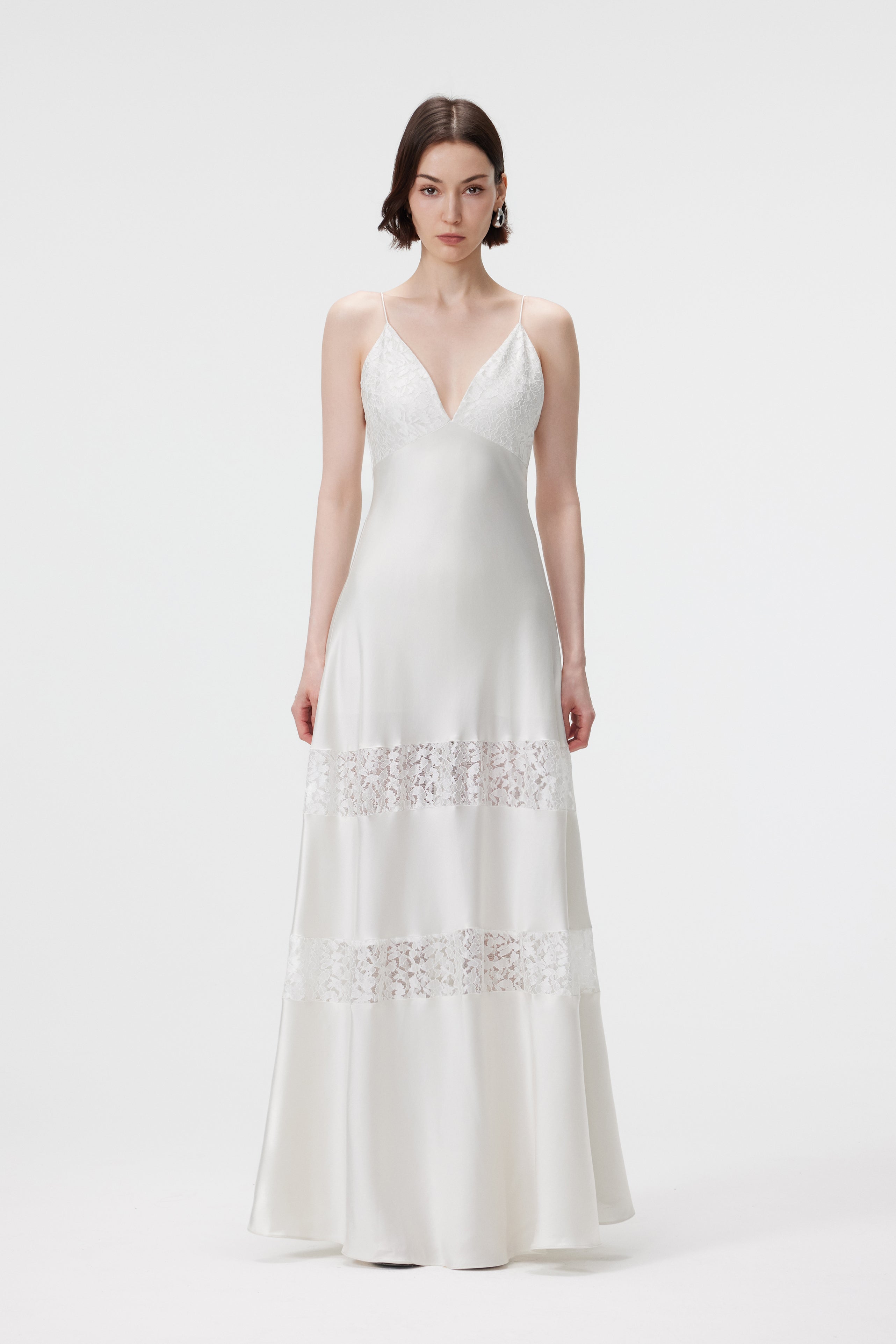 Front view of the AENSO Kaia dress in Pearl; a V-neck maxi dress in bias-cut Naia™ satin featuring delicate white lace-insert detailing and a fluid, statuesque silhouette.