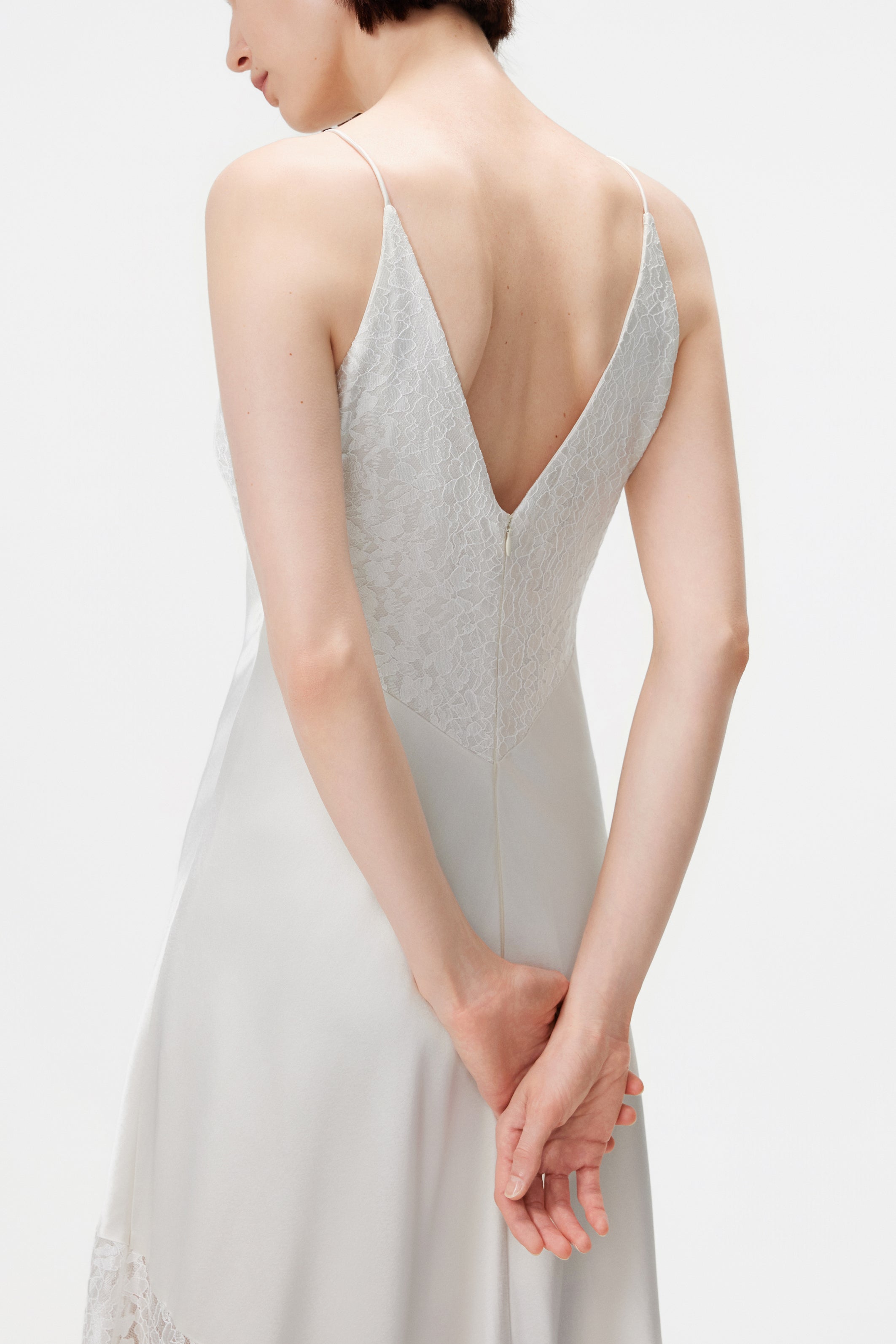 Close-up detail of the back of the Kaia dress, featuring the discreet invisible zipper closure, delicate straps, and the intricate texture of the sustainable white Naia™ lace.