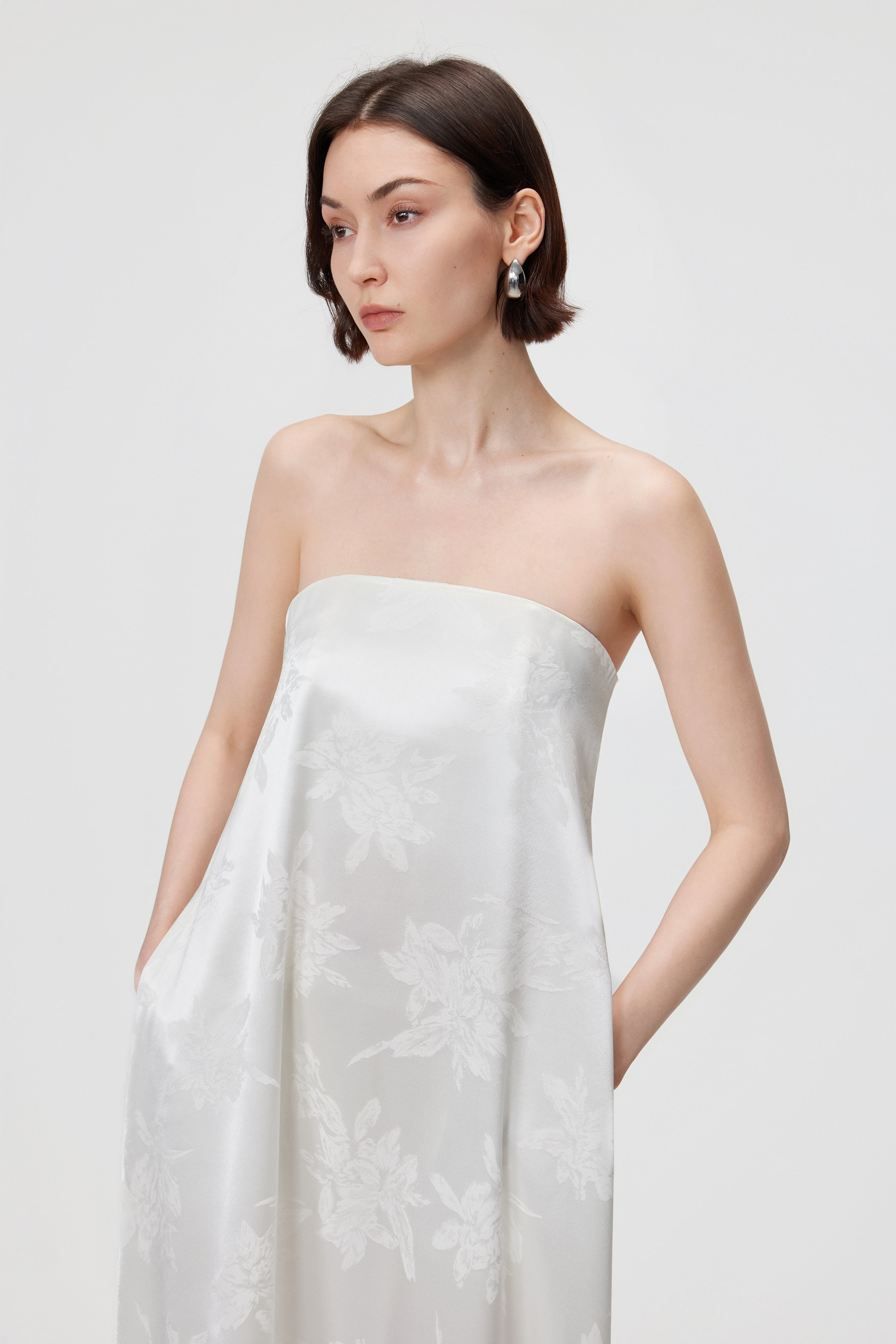 Close-up detail of the Aenso Iris dress in White, highlighting the functional internal side pocket and the intricate woven texture of the luxurious Naia™ Acetate floral jacquard in a crisp Ivory hue.