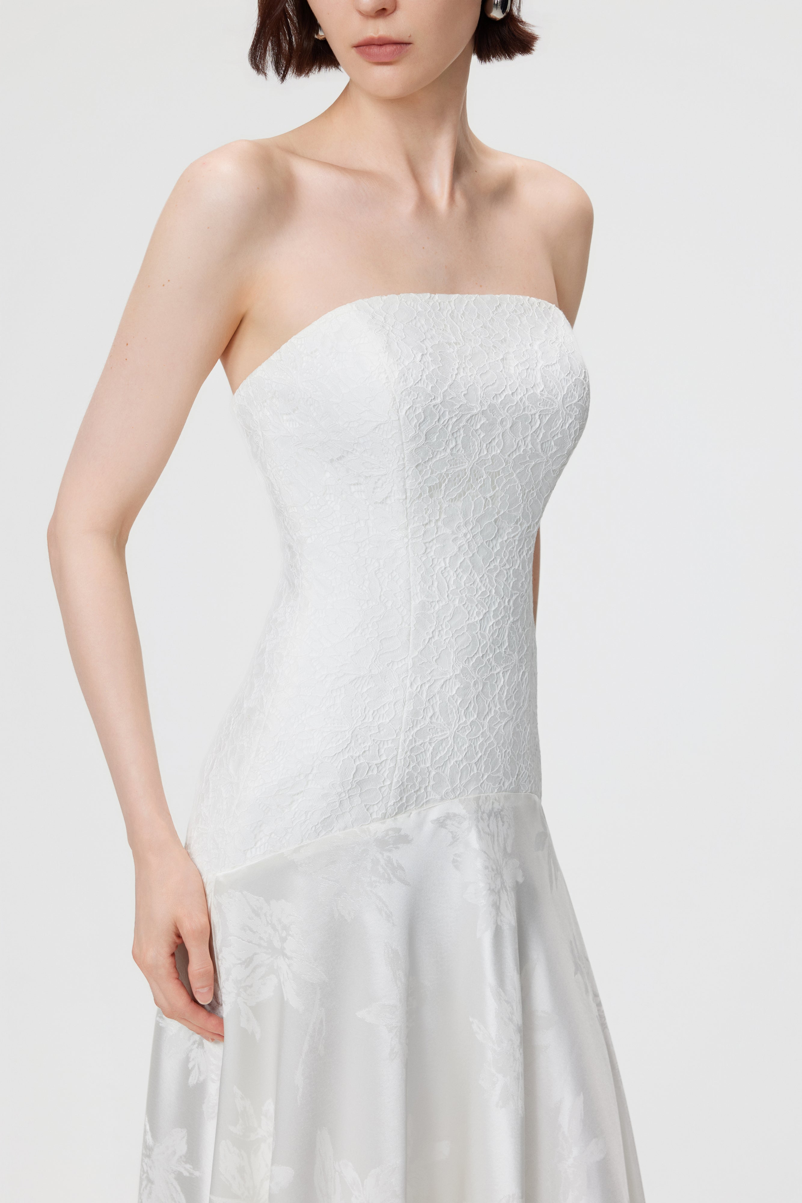 Close-up of the Vera Gown’s precision-paneled lace bodice and signature dropped curved waistline, showing the contrast between lace and high-luster floral jacquard.