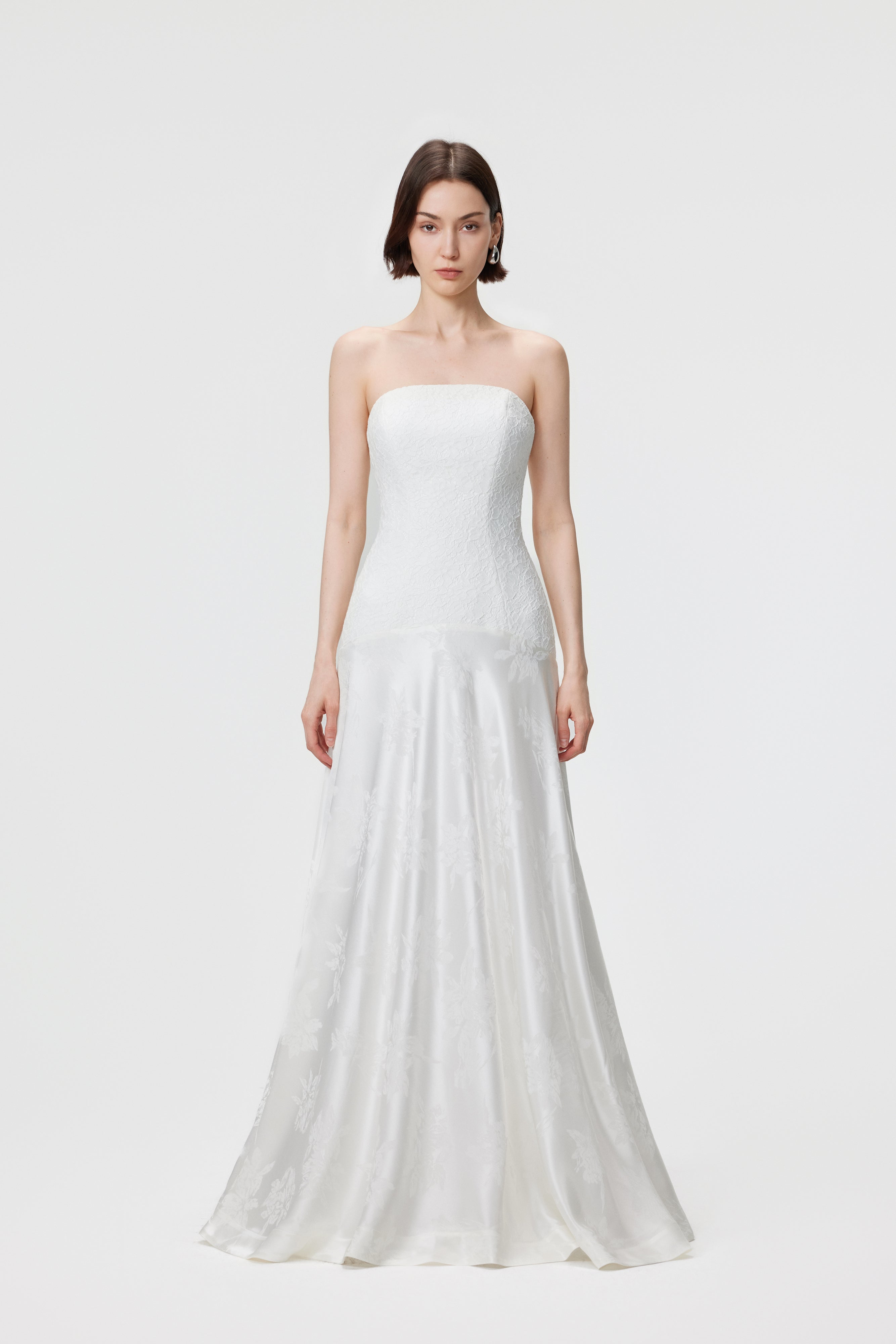 Aenso Vera Gown in Pearl white: featuring a strapless curved neckline, precision-panelled lace bodice, and a floor-length Naia™ acetate floral jacquard skirt with a signature dropped curved waist.