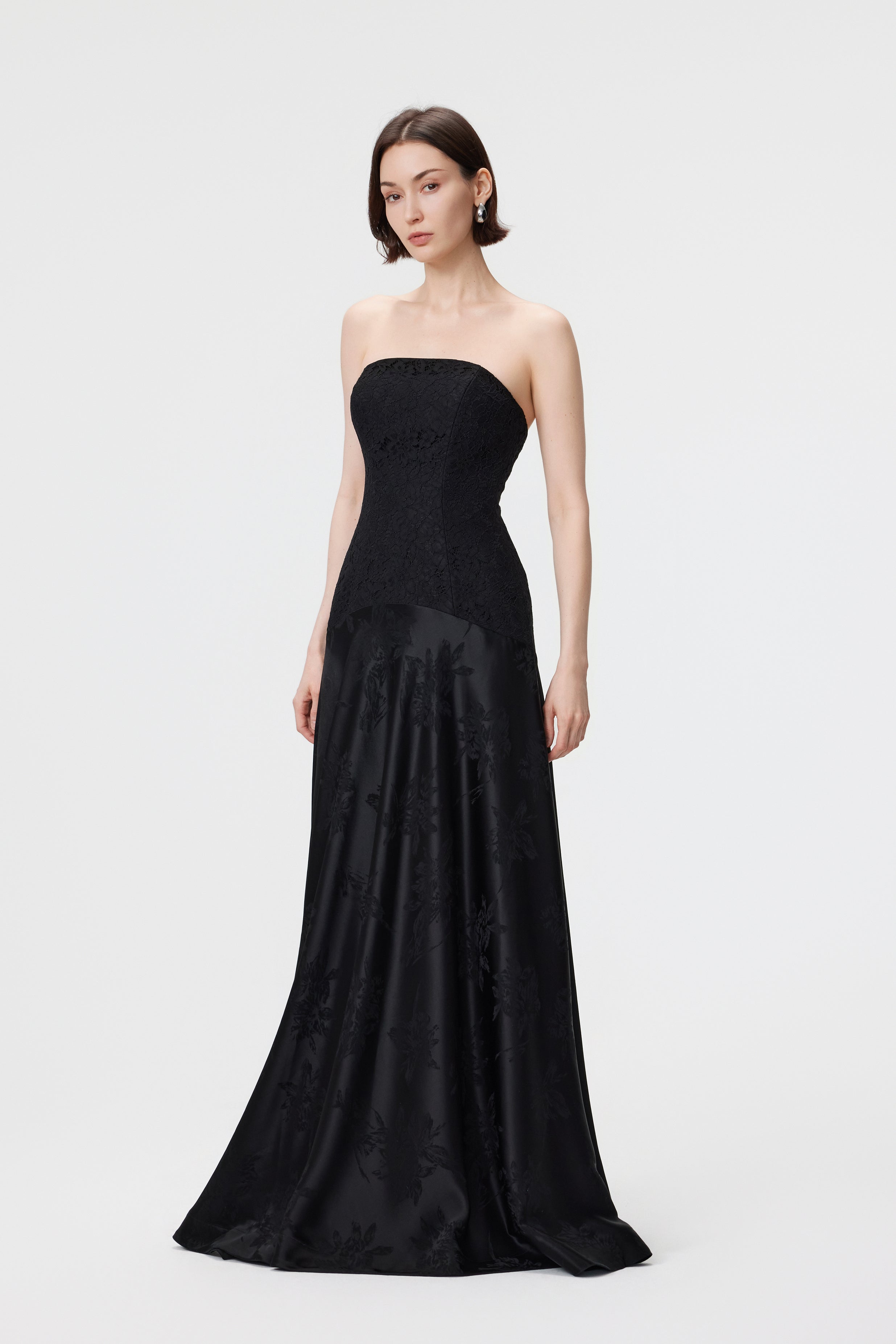 Side profile of the Vera gown in Black, highlighting the seamless transition from the signature dropped waistline to a weighted, rhythmic drape in high-luster Naia™ acetate.