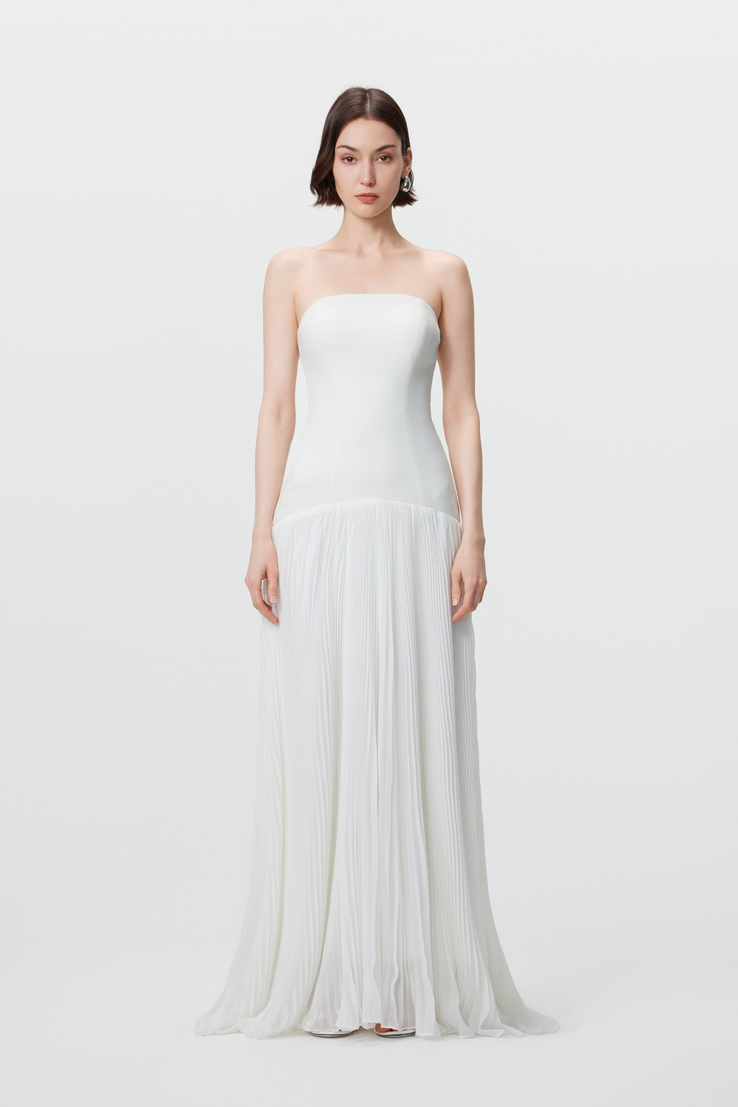 Front view of the AENSO Luna gown in White; a statuesque silhouette featuring a structured bustier bodice and voluminous sunray pleats in sustainable slubbed Naia™ acetate.