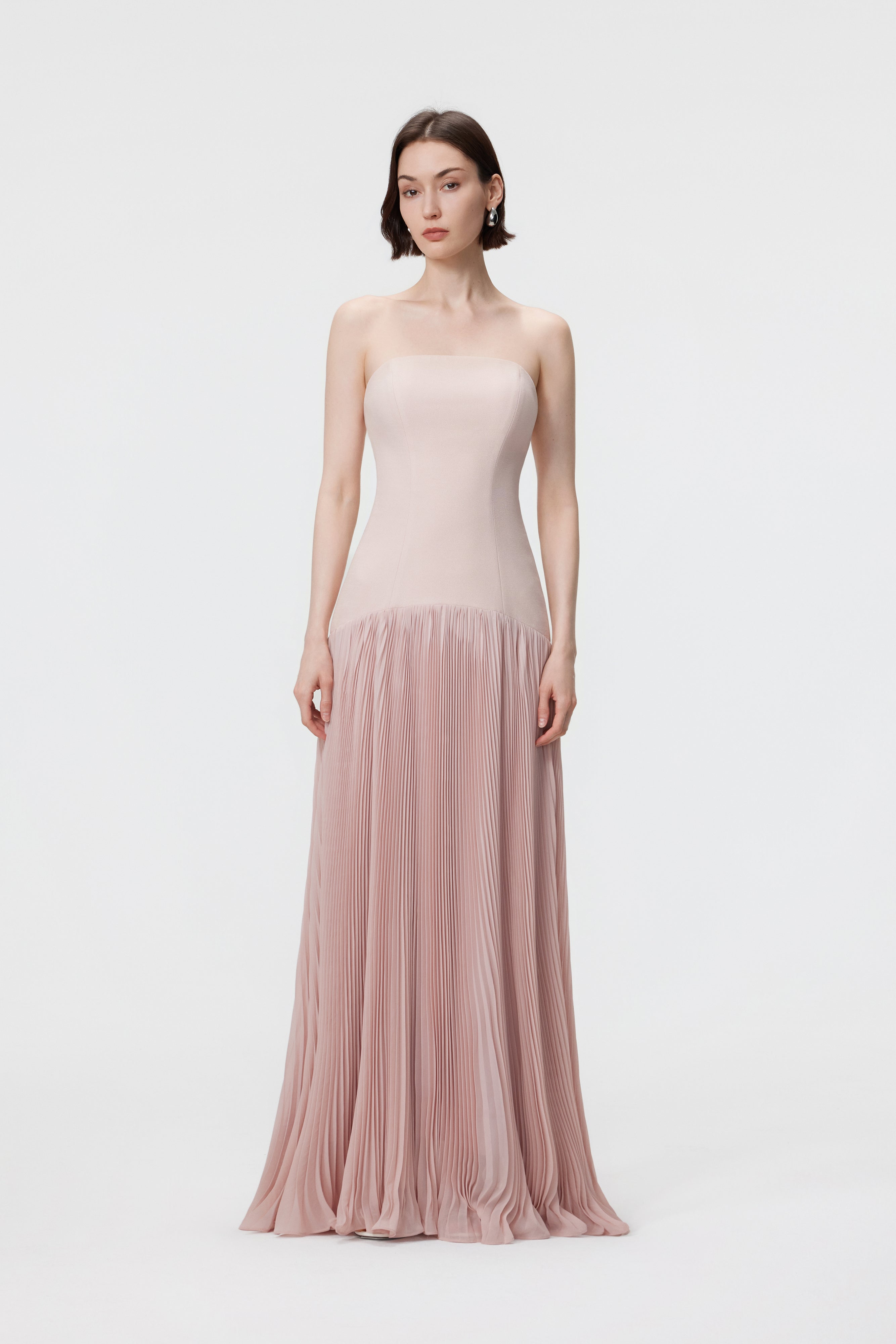 Front view of the AENSO Luna gown in Rosewater; a romantic pink silhouette featuring a structured bustier bodice and voluminous sunray pleats in specialized slubbed Naia™ acetate.