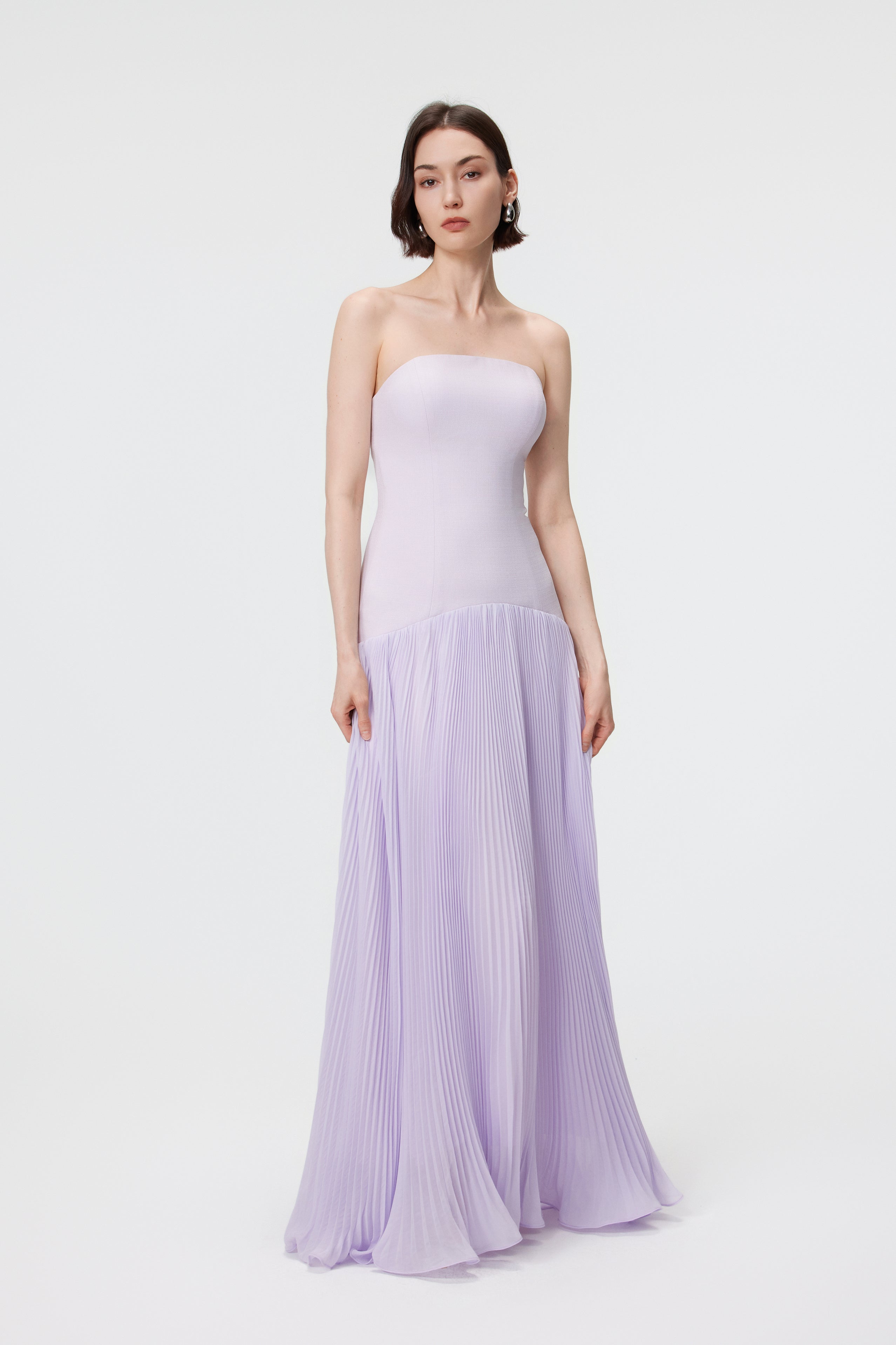 Static front view of the AENSO Luna gown in Cloudy Lilac; a refined and statuesque profile showcasing the precision-paneled bustier bodice and the crisp, vertical lines of the sunray pleats.