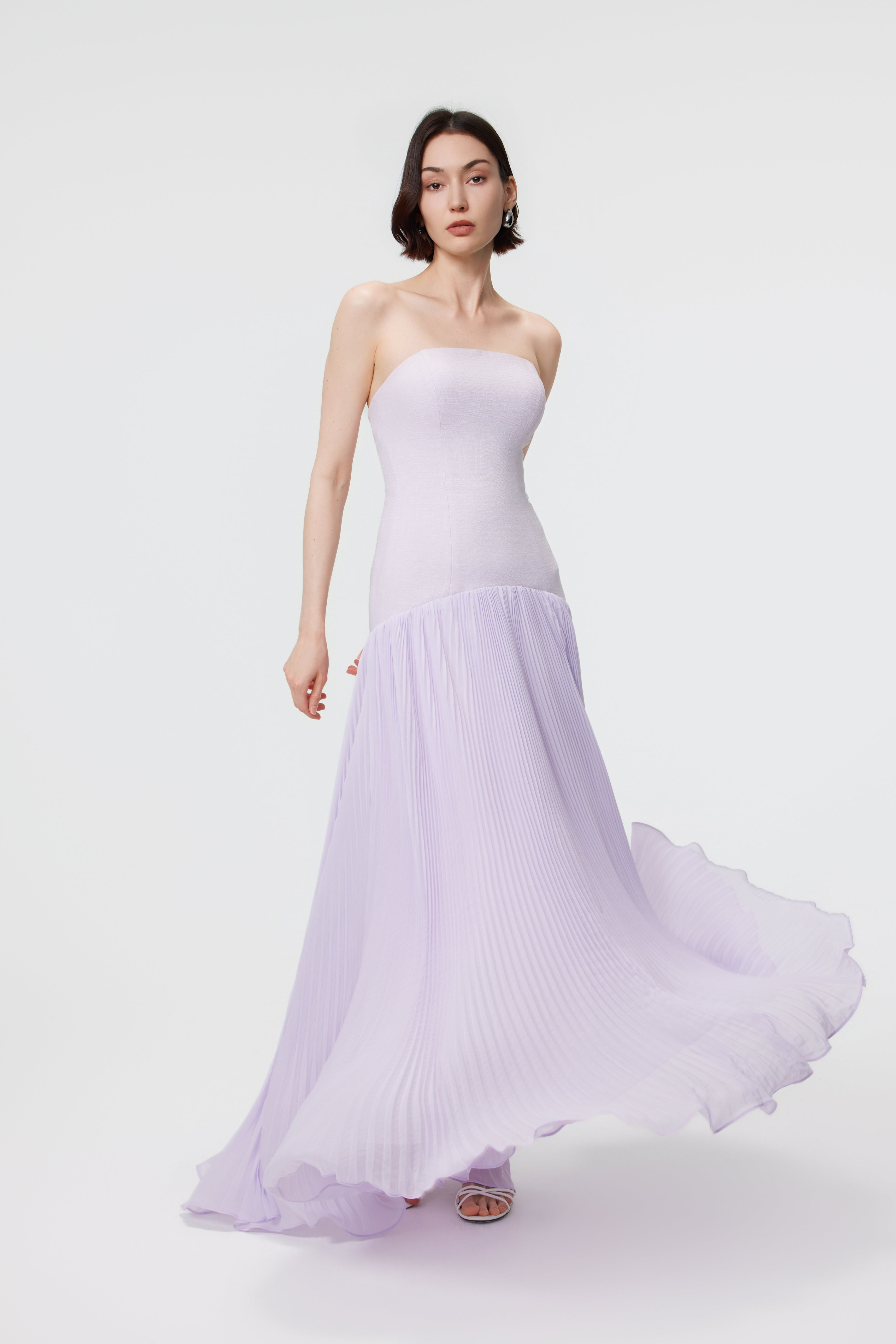Front view of the Luna gown captured in a soft breeze; the floor-length skirt billows gracefully to one side, highlighting the exceptionally lightweight nature of the sustainable artisanal manufacturing.