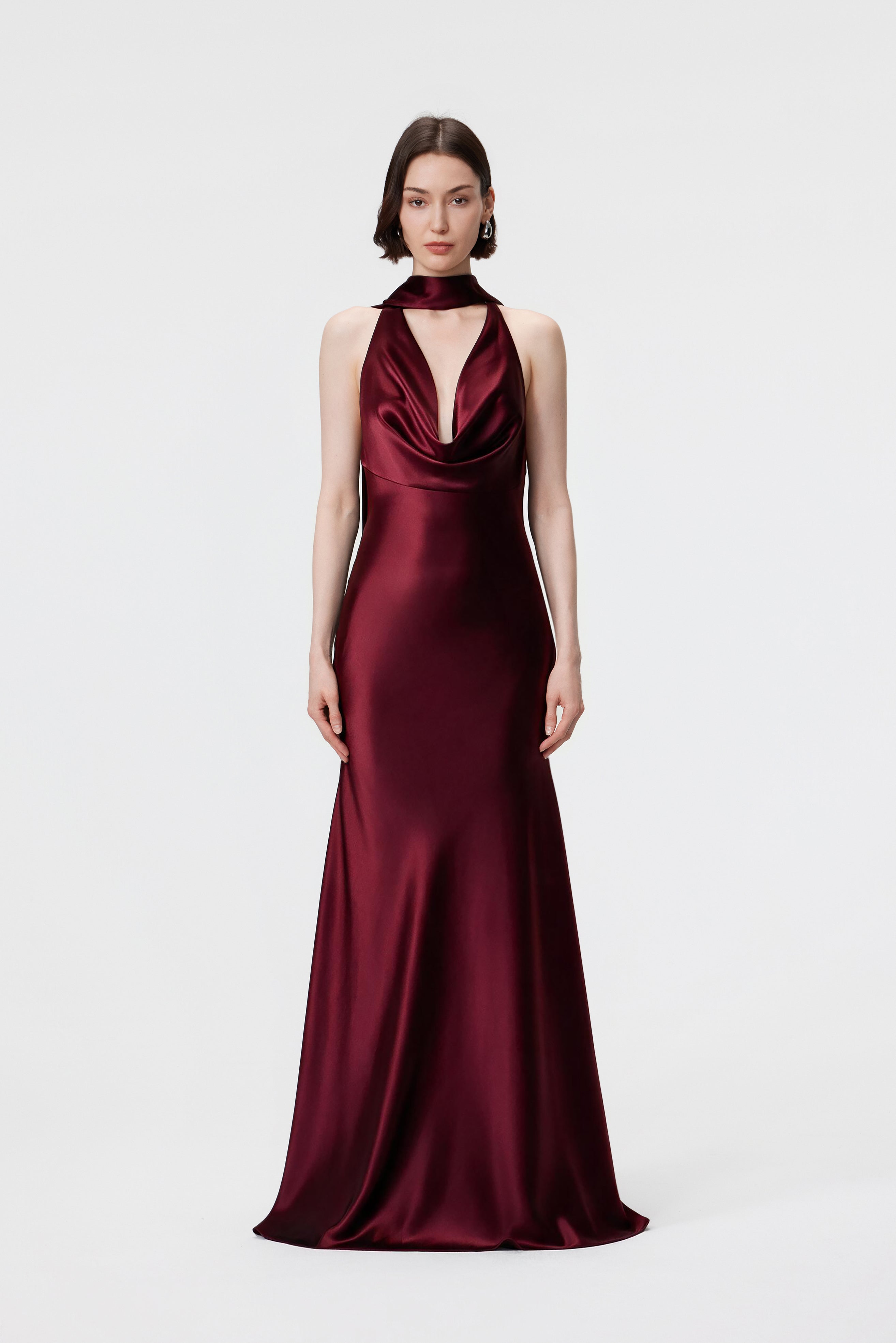 Model from the front wearing the Rhea dress in Red Berry, highlighting the draped cowl neckline and floor-length, bias-cut silhouette in luminous Naia™ Acetate satin.