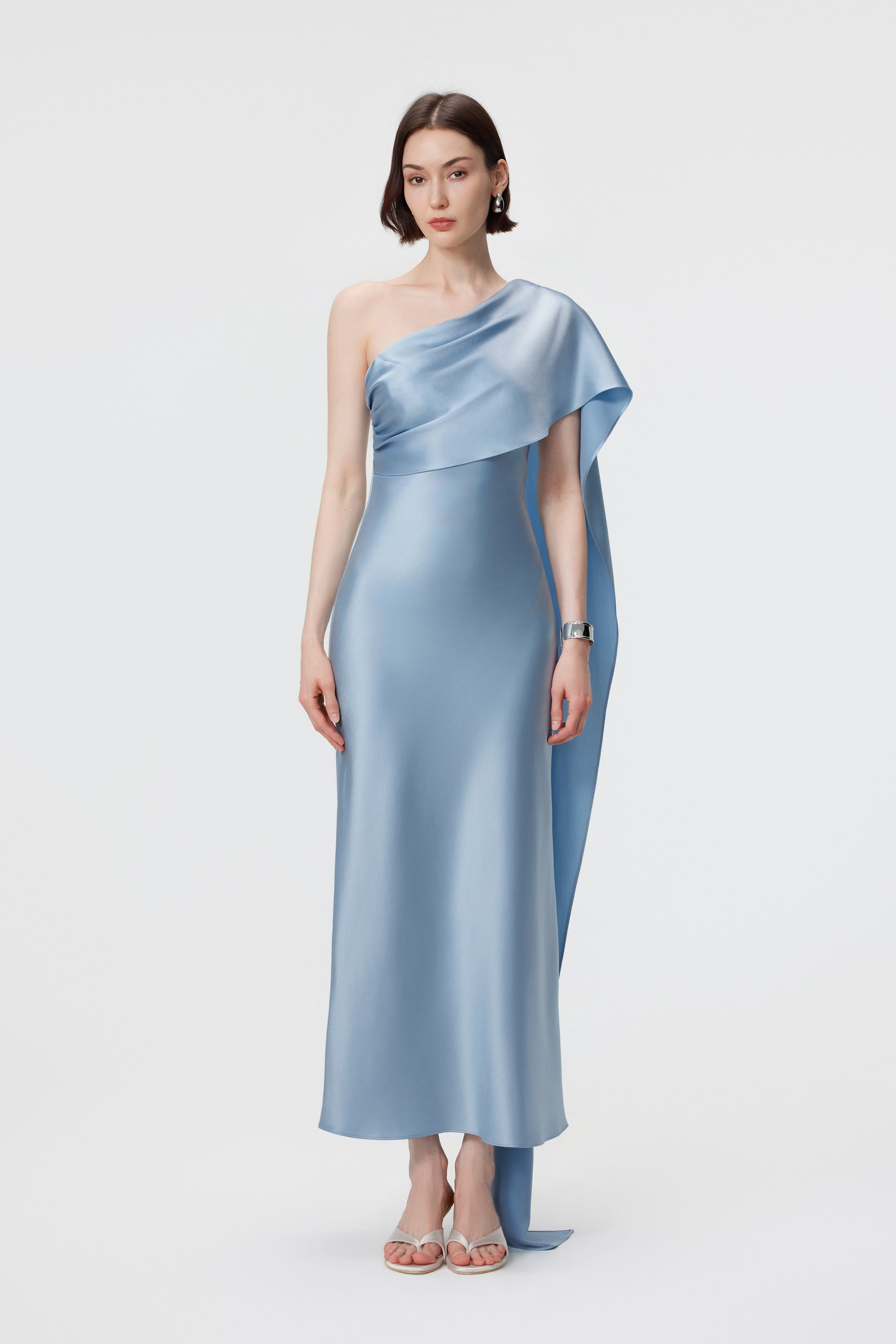The AENSO Lyra dress in Glacial Mist; featuring The Asymmetric style with a clean one-shoulder neckline and a fluid, trailing scarf drape.