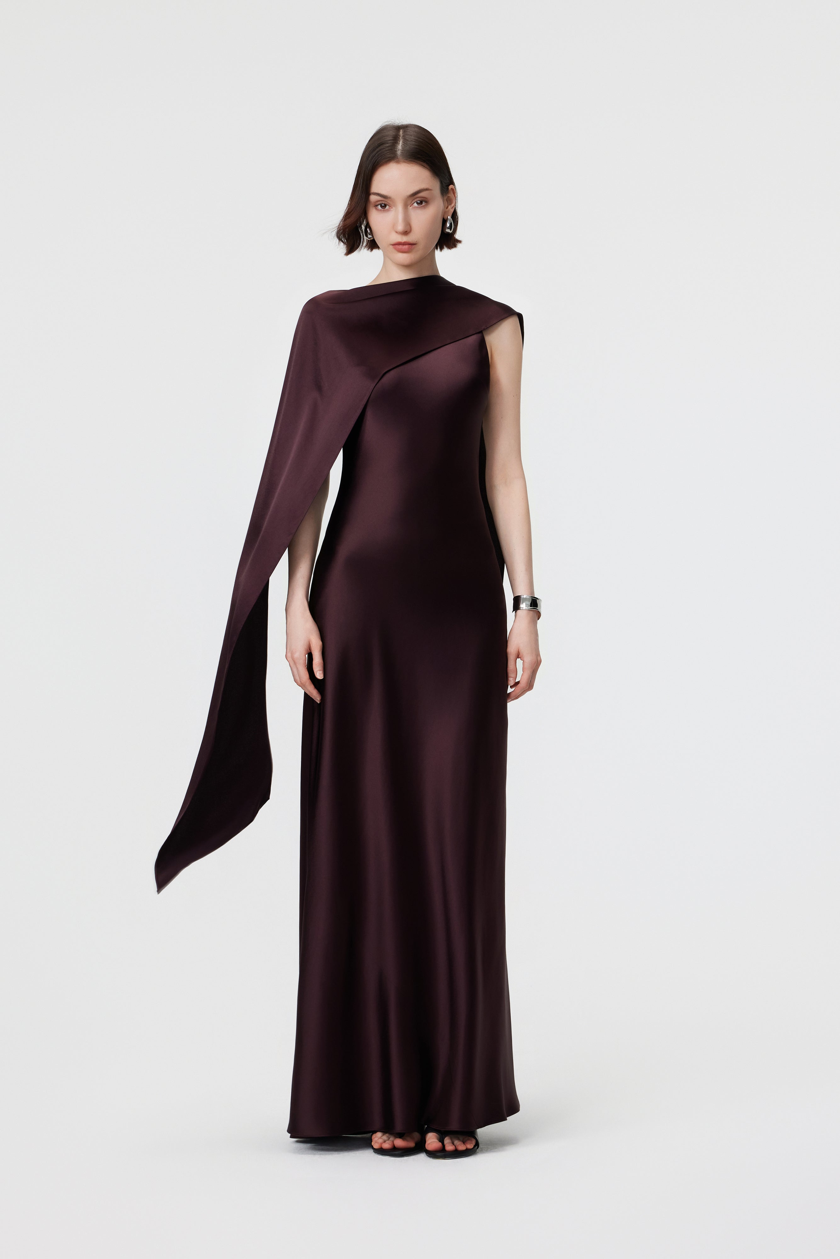 AENSO Elara Gown in Espresso, styled as an asymmetric cape to demonstrate the multi-way integrated scarf in liquid-like satin.