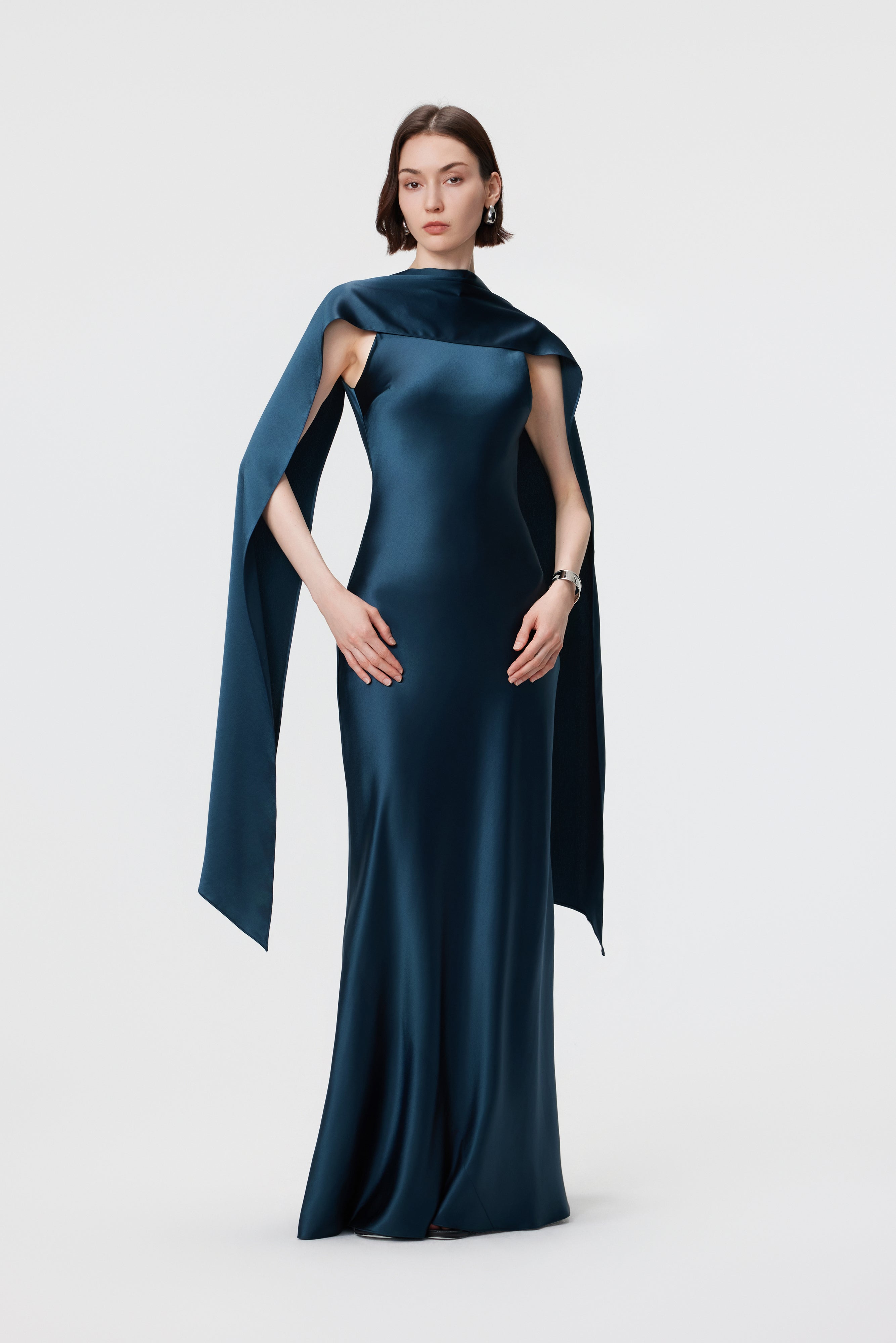 Static front view of the AENSO Elara gown in Midnight Teal; a signature column silhouette featuring a dramatic, convertible high-neck drape in smooth, high-luster Naia™ acetate.