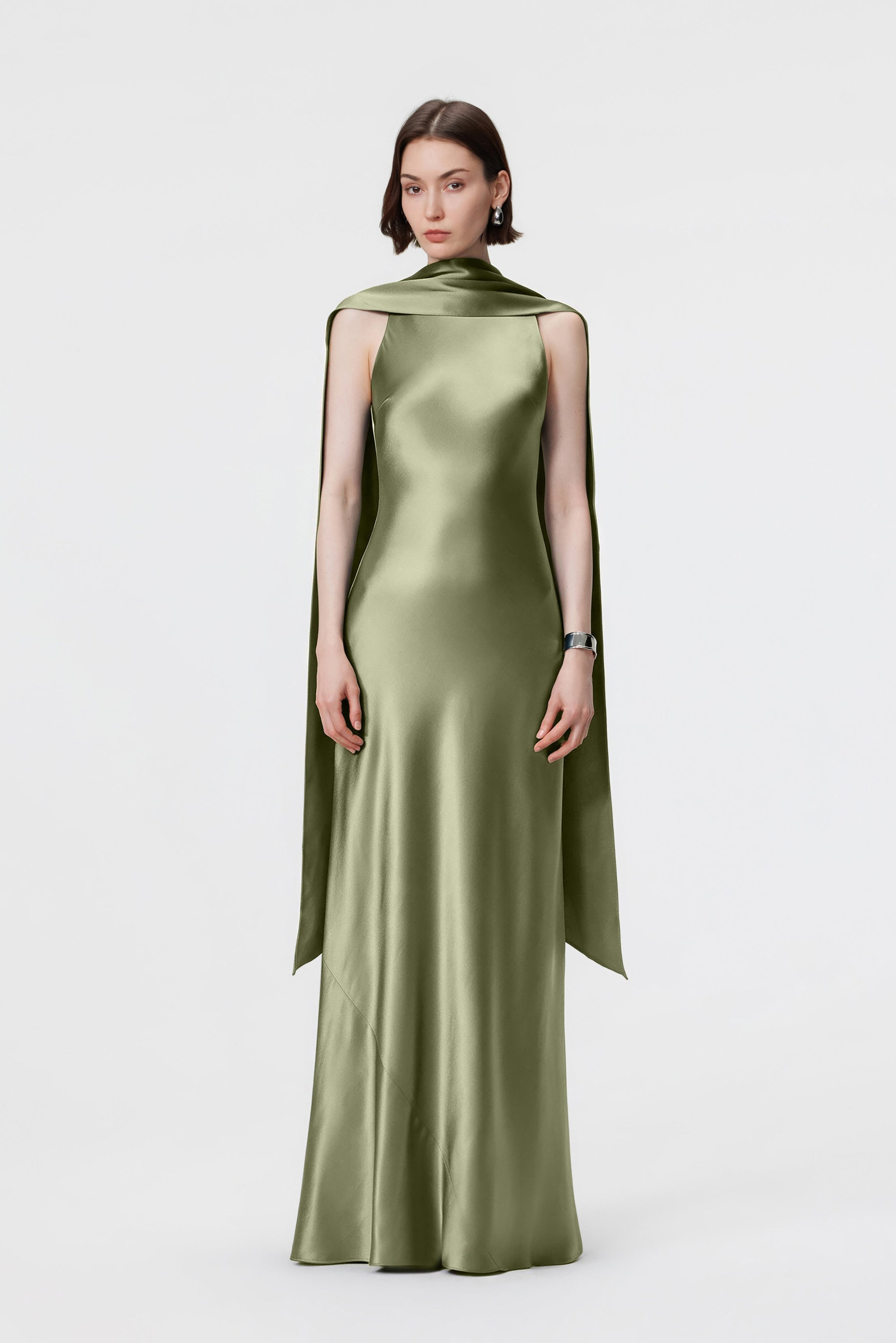 Front view of a woman wearing a high-neck bias-cut satin gown in Moss green with a floor-length cape back.