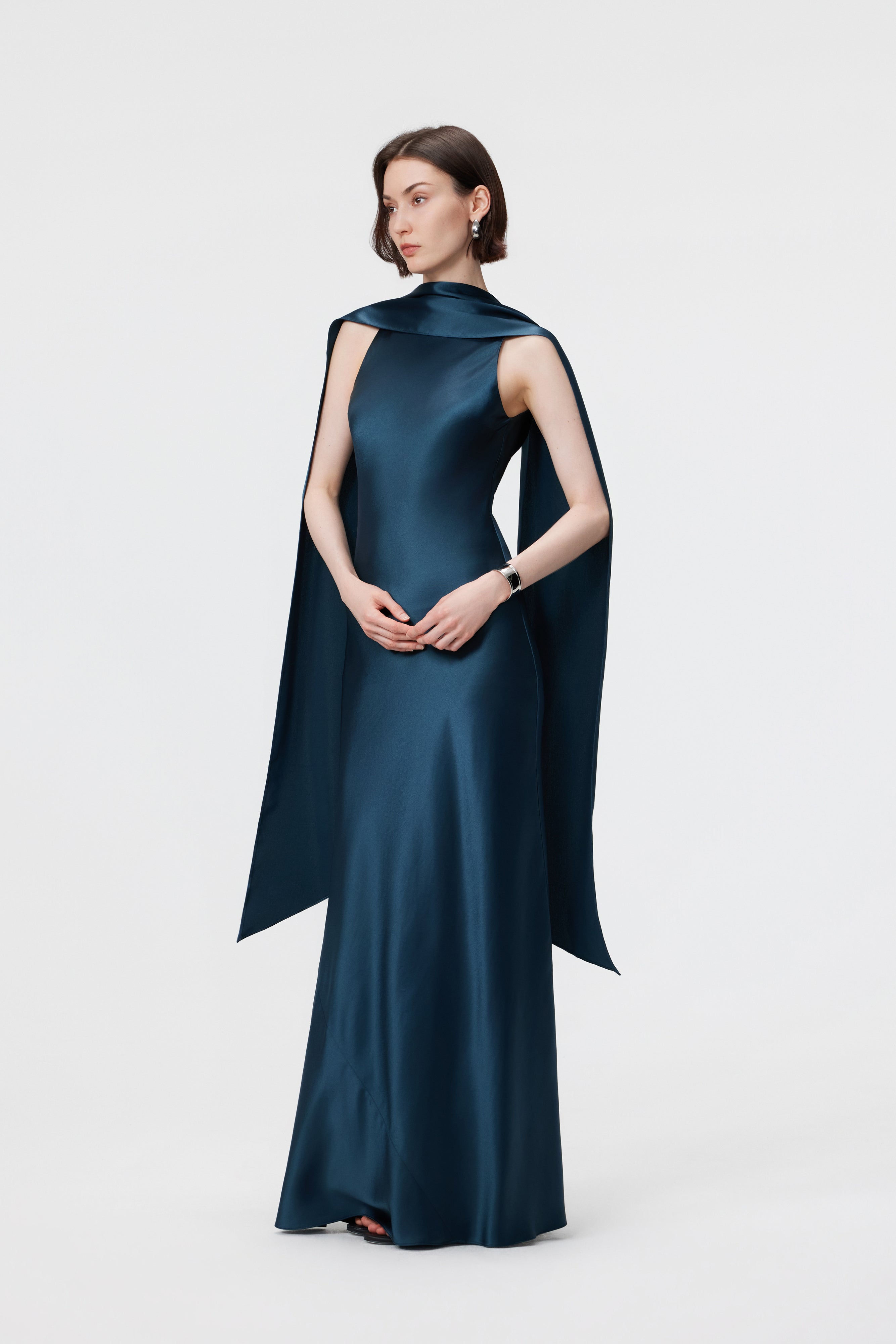 Side profile of the AENSO Elara gown in Midnight Teal; highlighting the precision-structured high-neckline and the clean, architectural line of the signature column silhouette.