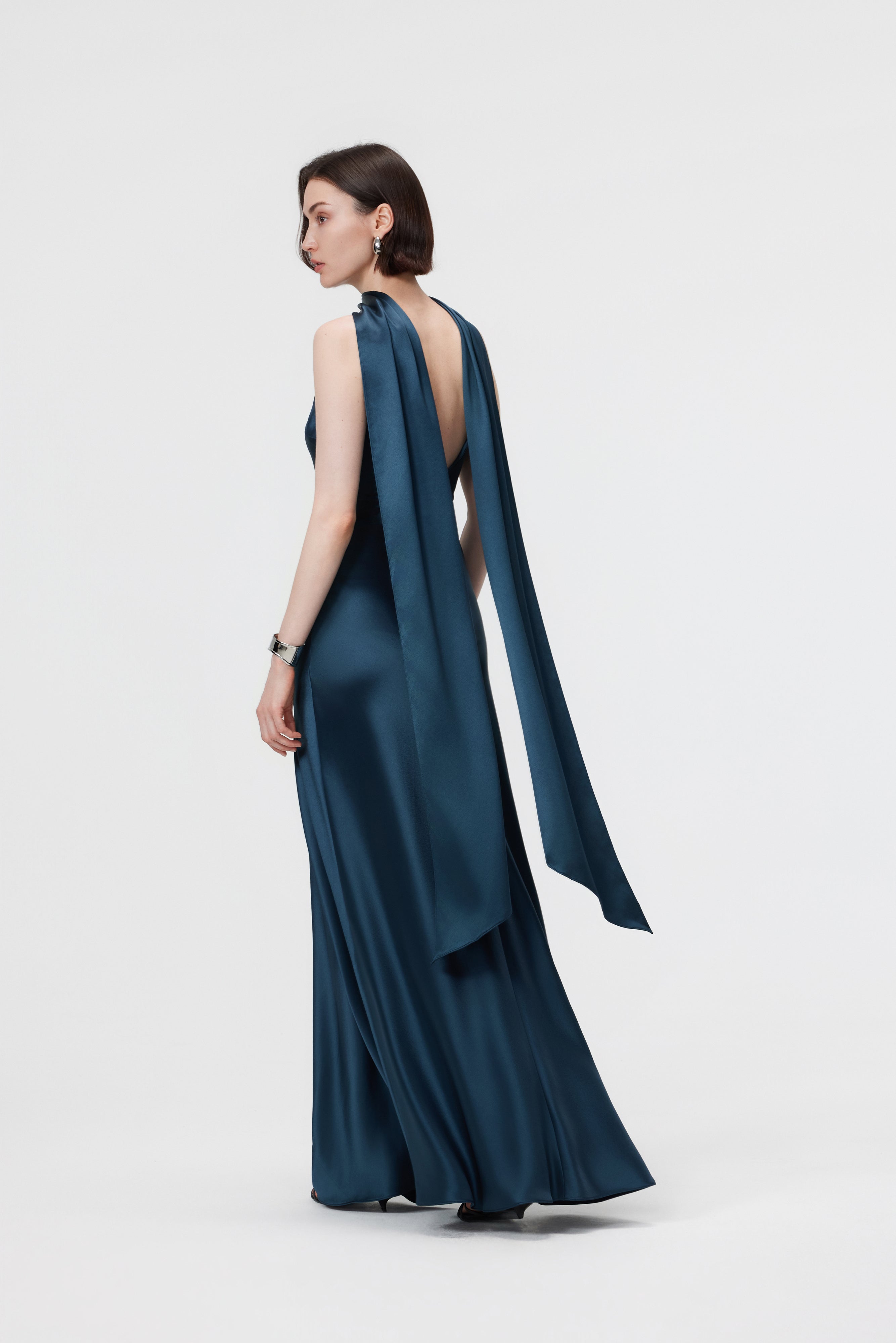 Back view of the AENSO Elara gown in Midnight Teal; showcasing the minimal form and the continuous, rich luster of the sustainable Naia™ acetate.