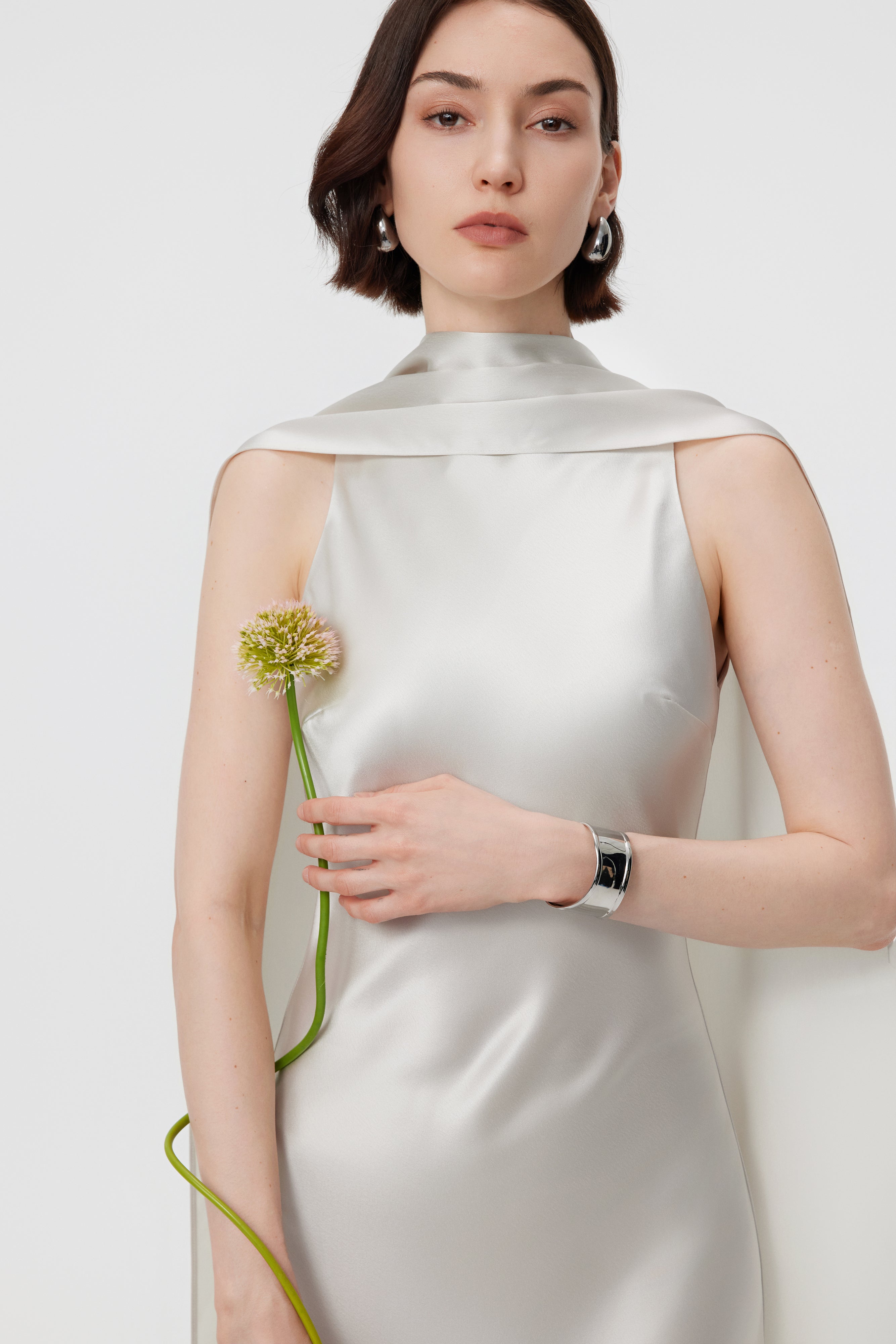 Detailed close-up of the AENSO Elara gown’s integrated scarf neckline in Pearl; capturing the luminous clarity and architectural folds of the high-luster Naia™ Acetate.