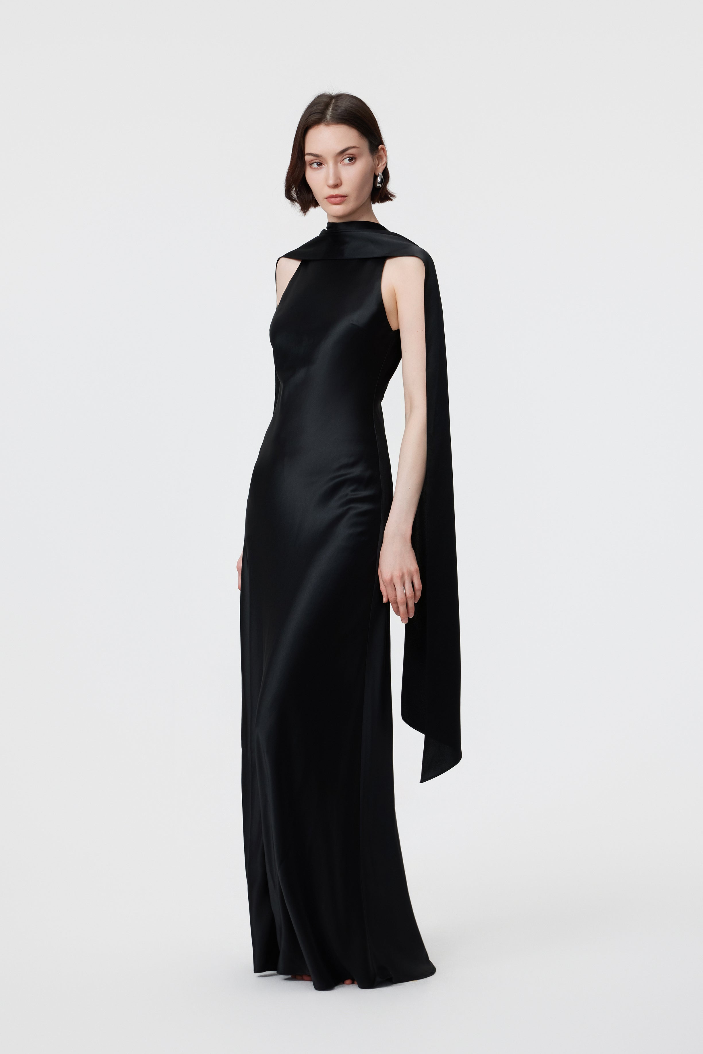 Side profile of the AENSO Elara gown in Black; showcasing the precision of the integrated high-neck scarf and the clean, architectural line of the bias-cut silhouette in high-luster Naia™ Acetate.